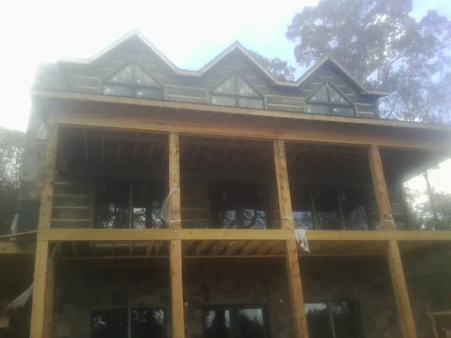 Dormers and porch framing on a large log home under construction — Roof Coating work by our crew in Fletcher